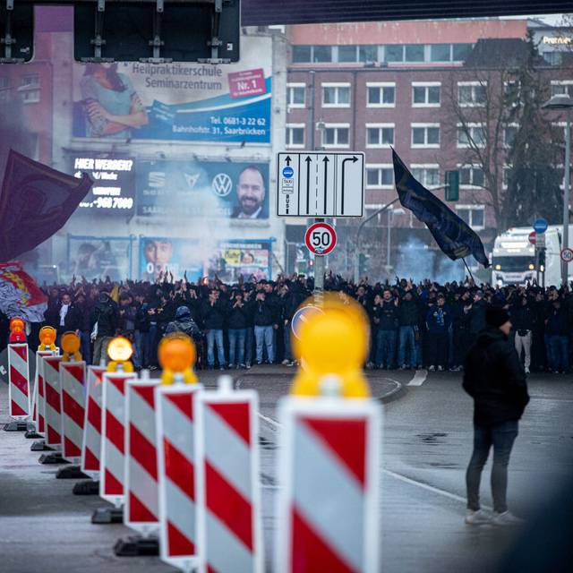 Fußballfans stehen in einem Tunnel und werden von Polizisten begleitet.