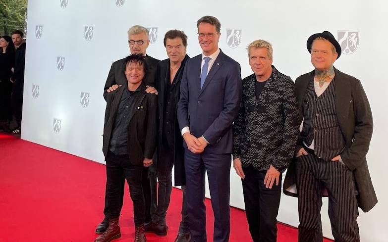 Die Toten Hosen und NRW-Ministerpräsident Hendrik Wüst auf dem rote Teppich. Die Toten Hosen bekommen den NRW-Staatspreis für  ihr kulturelles Lebenswerk und für ihre sozialen Einsatz.