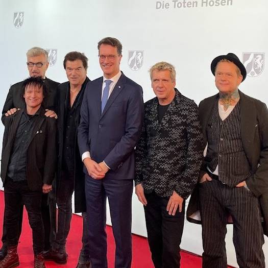 Die Toten Hosen und NRW-Ministerpräsident Hendrik Wüst auf dem rote Teppich. Die Toten Hosen bekommen den NRW-Staatspreis für  ihr kulturelles Lebenswerk und für ihre sozialen Einsatz.