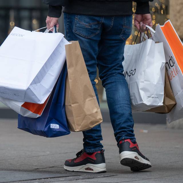 Ein Mann trägt viele Einkaufstaschen nach einer Shoppingtour