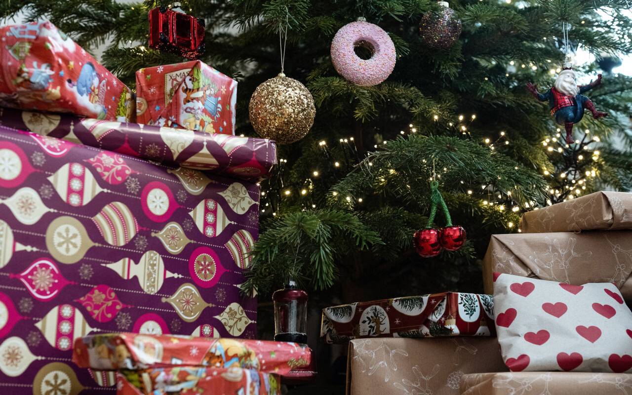 Eingepackte Geschenke liegen unter einem geschmückten Weihnachtsbaum.