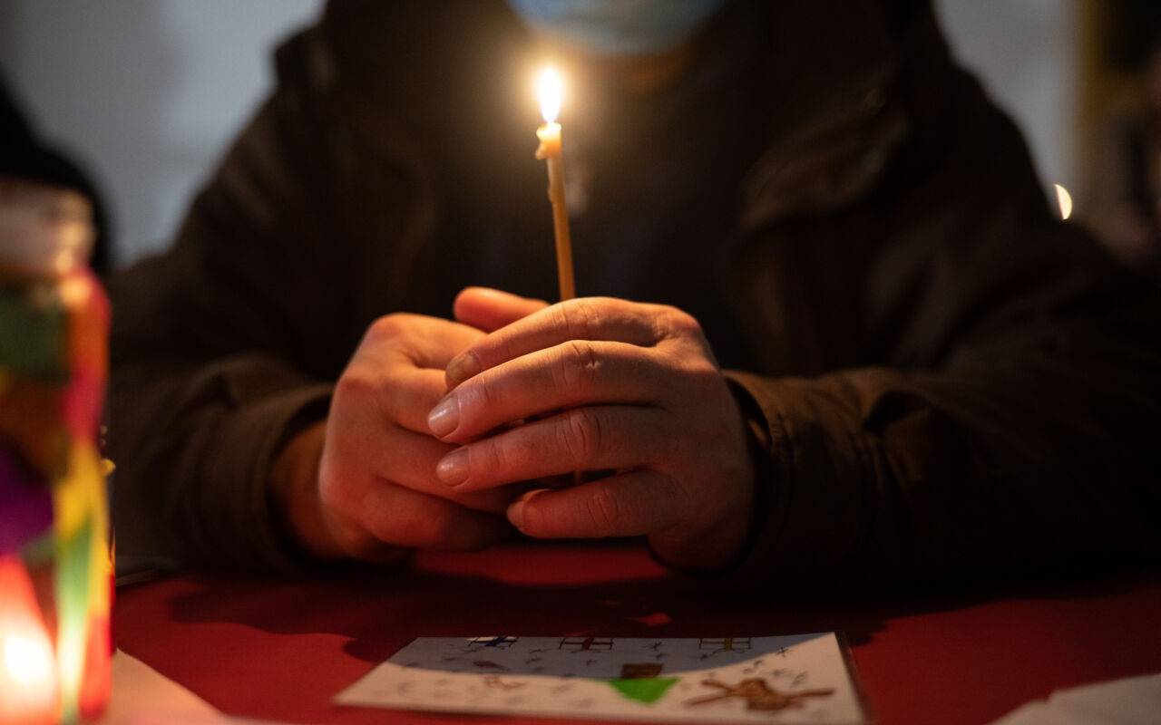 Besucher sitzt in der Weißfrauen Diakoniekirche mit einer Kerze beim Gottesdienst an einem Tisch. Die Kirche im Bahnhofsviertel öffnet bei der Veranstaltung am Heiligen Abend ihre Türen und schließt sie erst am ersten Weihnachtsfeiertag wieder. Das Angebot mit Gottesdienst, Weihnachtsessen, Musik und Übernachtungsmöglichkeit richtet sich an alle Menschen im Bahnhofsviertel. Hauptsächlich sind die Besucher jedoch wohnungslos oder haben sehr geringe finanzielle Mittel zur Verfügung.