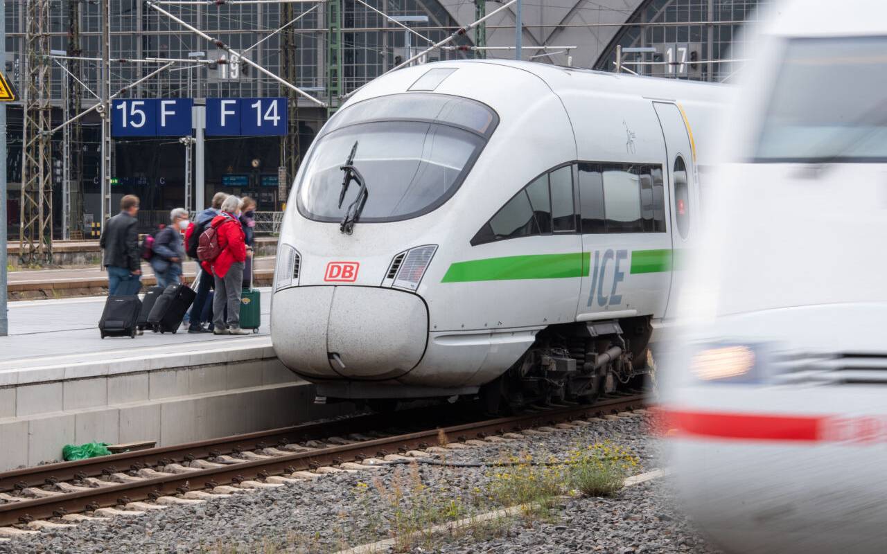 Menschen steigen mit Koffern in einen ICE-Zug der Deutschen Bahn ein.