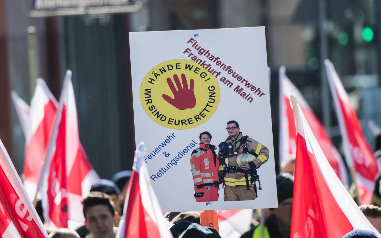in Plakat "Hände weg! Wir sind Eure Rettung" wird von einem Mitglied der Flughafen Feuerwehr Frankfurt auf einer Demonstration gehalten. Rettungskräfte demonstrieren in der Banken-Metropole für mehr Respekt und gegen Gewalt bei ihren Einsätzen