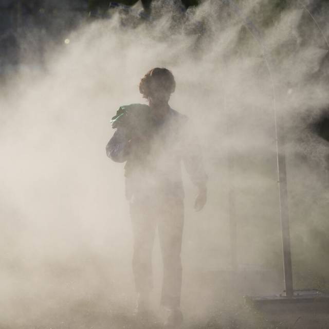 Olympia, Paris 2024, eine Person geht durch einen Sprühnebel-Zerstäuber und kühlt sich ab.