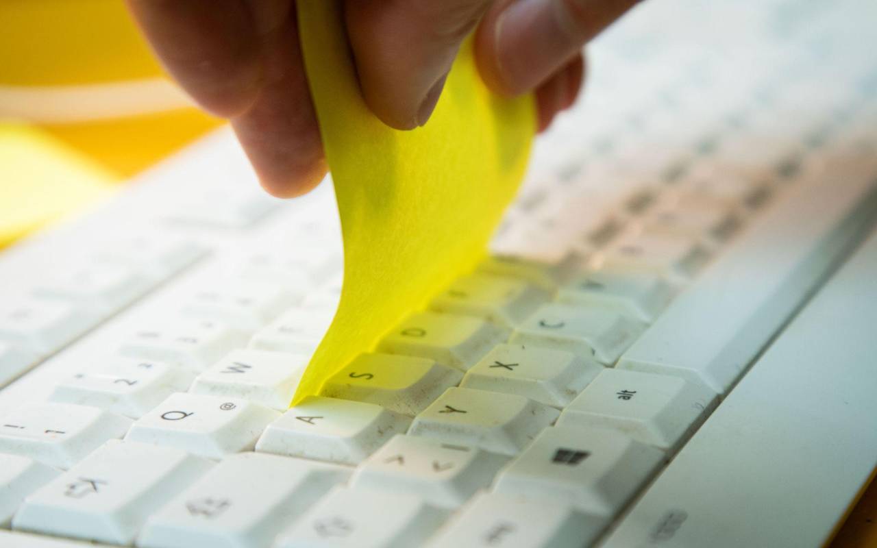 Klebezettel wird zwischen die Tastenreihen einer Tastatur gezogen