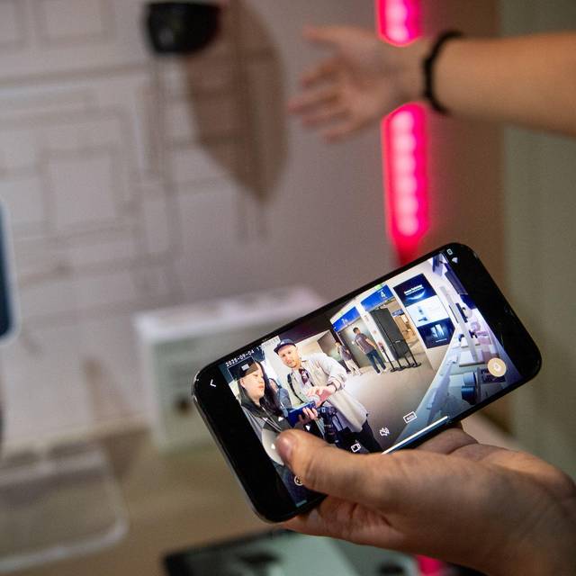 Eine Frau steuert mit einem Smartphone eine Ueberwachungskamera