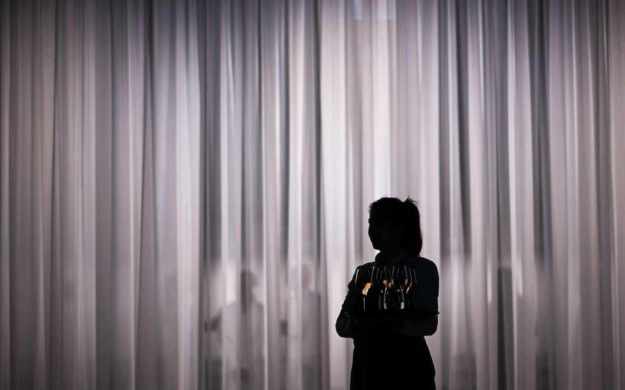 Eine Servicemitarbeiterin steht vor einem hellen Vorhang