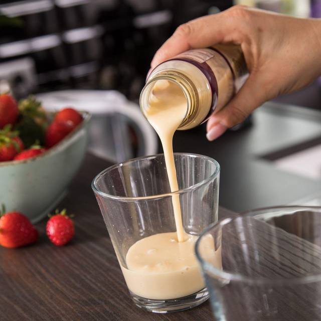Eine Frau gießt ein Fertig-Getränk in ein Glas