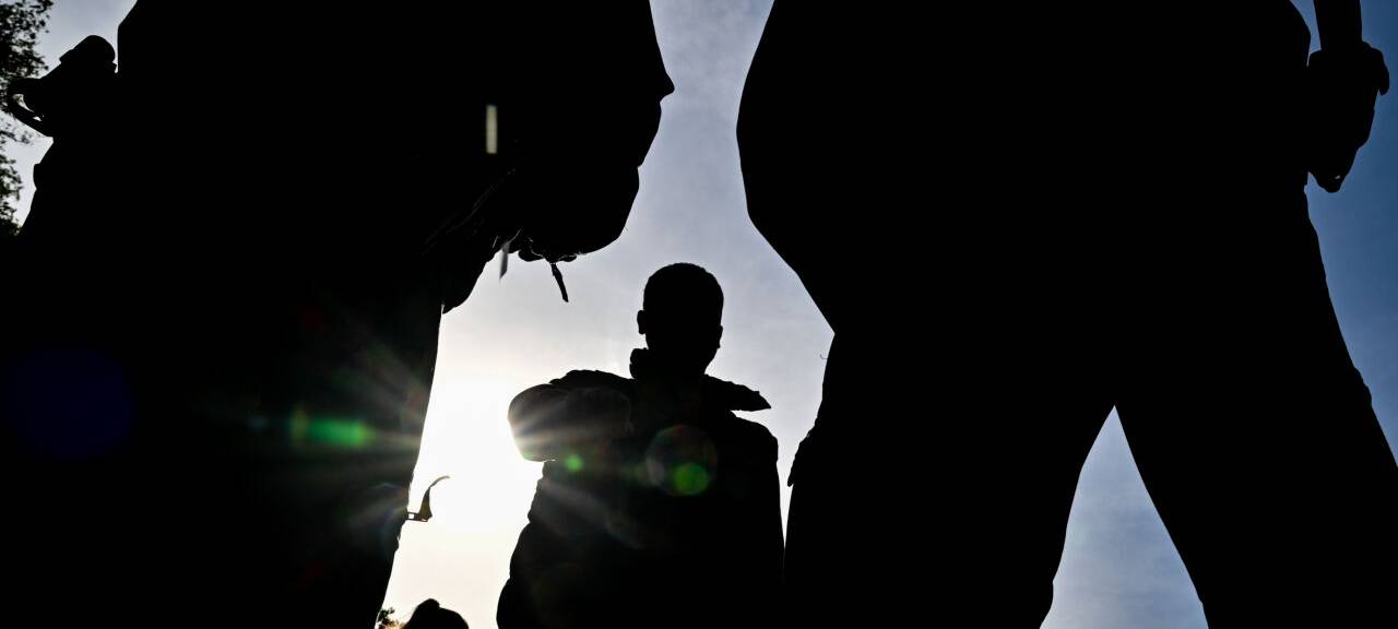 Beamten der Bundespolizei stehen vor einem unerlaubt eingereisten Migrant (M). der nahe Forst (Lausitz) aufgegriffen wurde