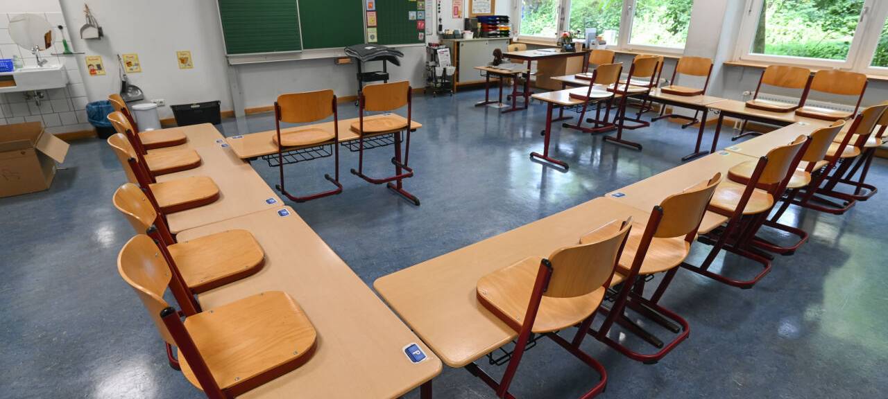 Stühle stehen in einem leeren Klassenzimmer auf den Tischen.