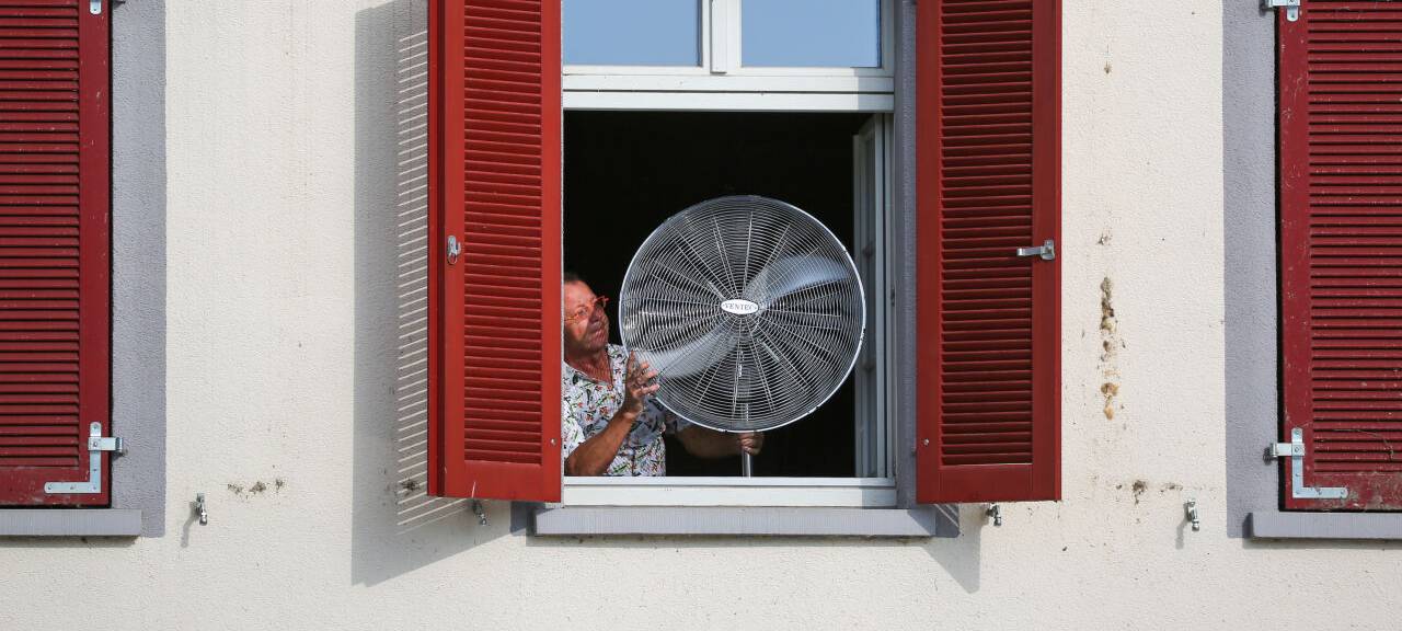 Ein Mann stellt am Morgen einen Ventilator an sein geöffnetes Fenster. Für viele Tage im Sommer sind Temperaturen über 30 Grad Celsius vorhergesagt.