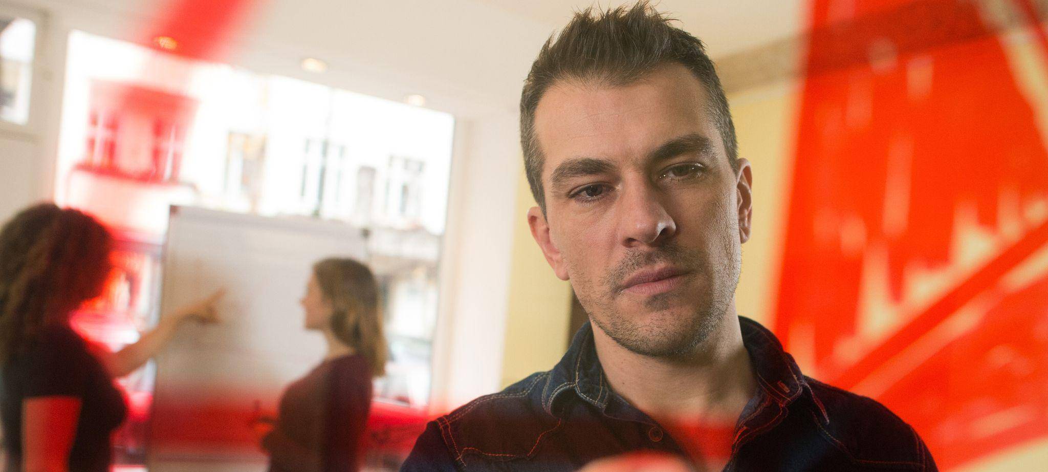 Mann malt zur Visualisierung einen Kreis an eine Plexiglasscheibe