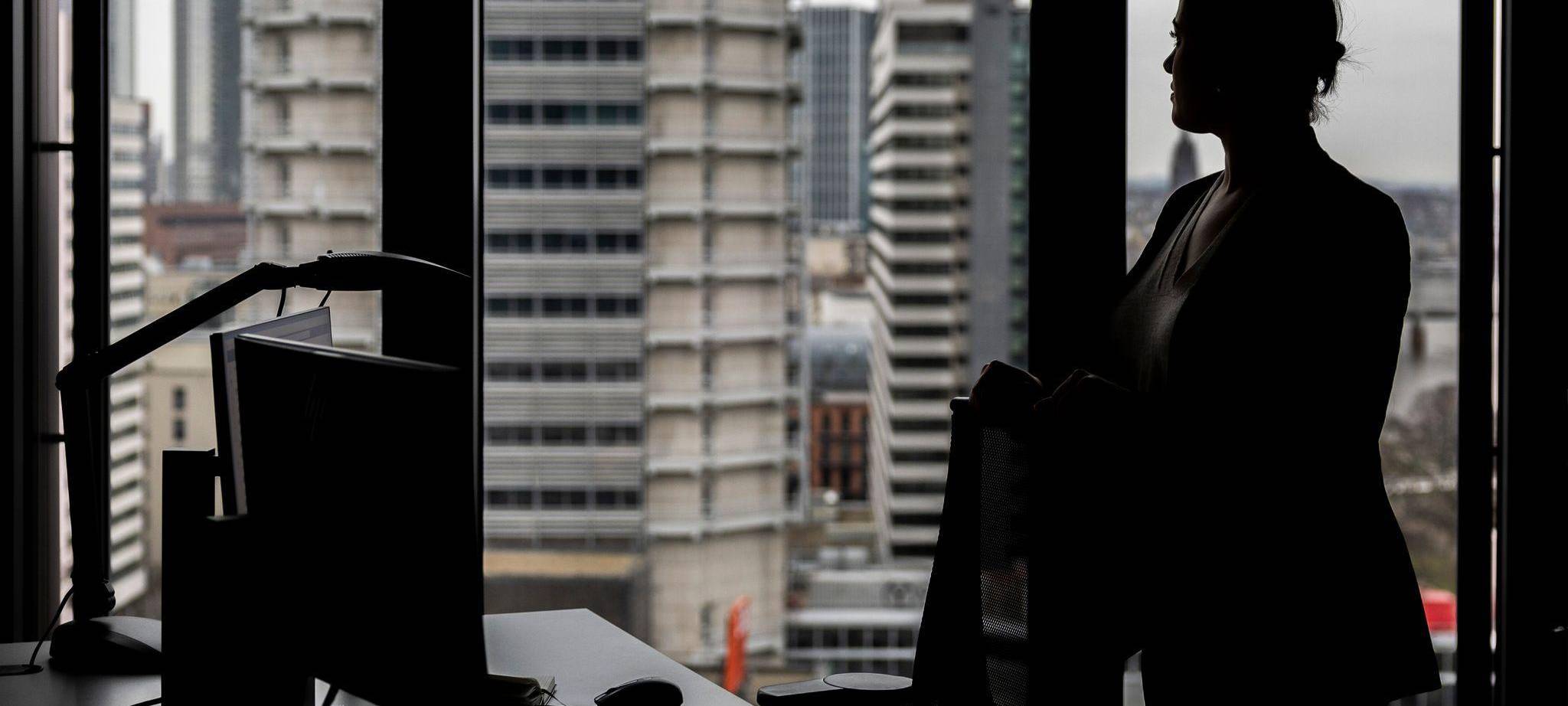 Frau steht an ihrem Arbeitsplatz am Fenster