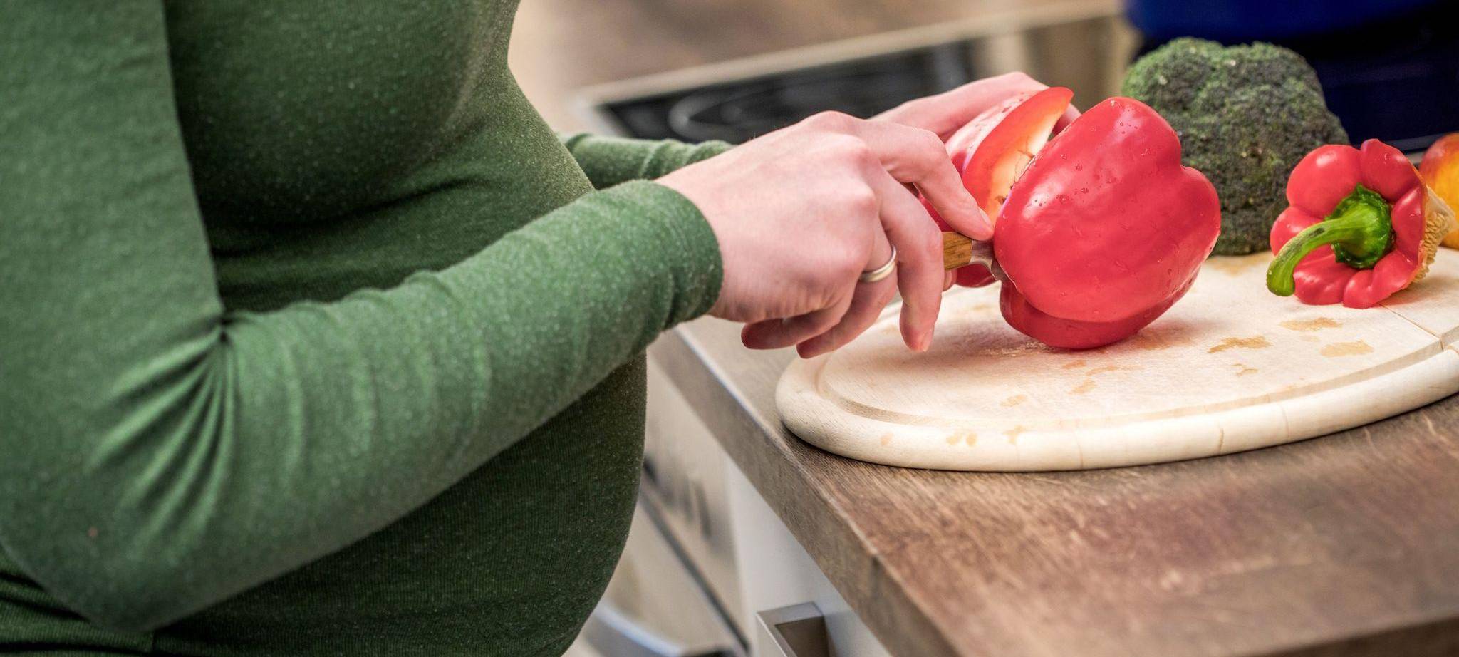 Schwangere Frau kocht mit Gemüse