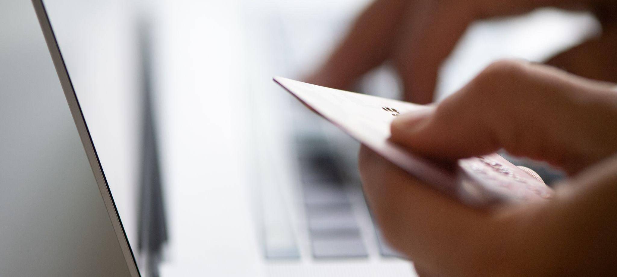 Mann sitzt mit Kreditkarte vor einem Laptop