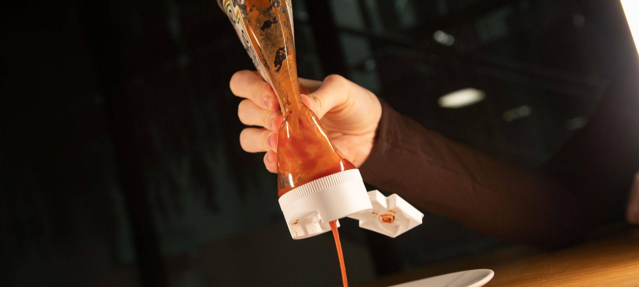 Frau drückt Ketchup aus einer Flasche