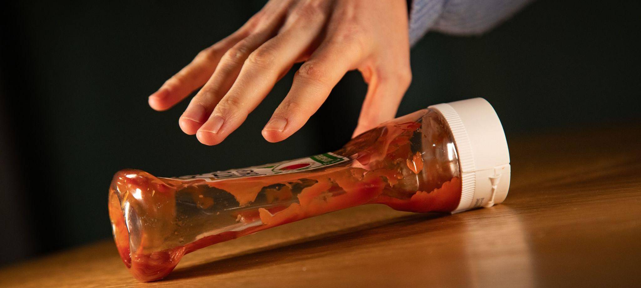 Frau greift nach einer fast leeren Ketchup-Flasche