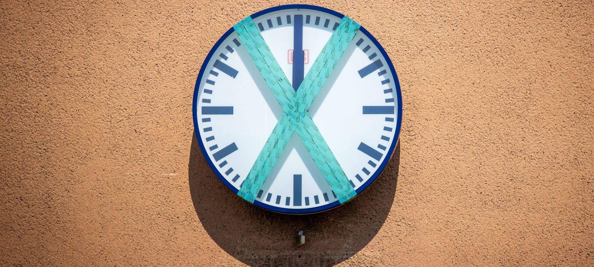 Eine abgeklebte Bahnhofsuhr hängt an einer Wand