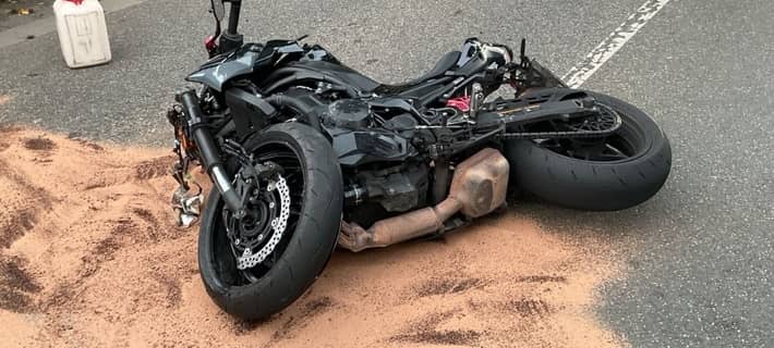Das beschädigte Motorrad liegt auf der Fahrbahn. Rund um das Fahrzeug wurde Bindemittel auf ausgelaufene Betriebsstoffe aufgebracht.